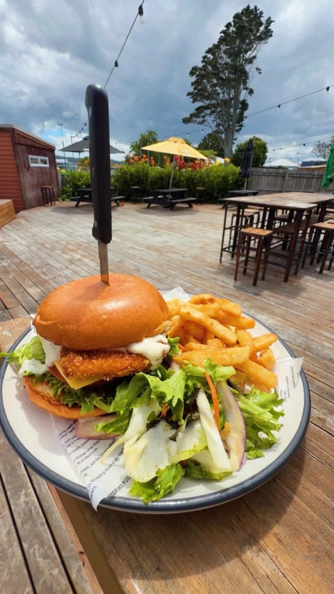 Crispy chicken burger with fries and side salad on the outdoor deck
