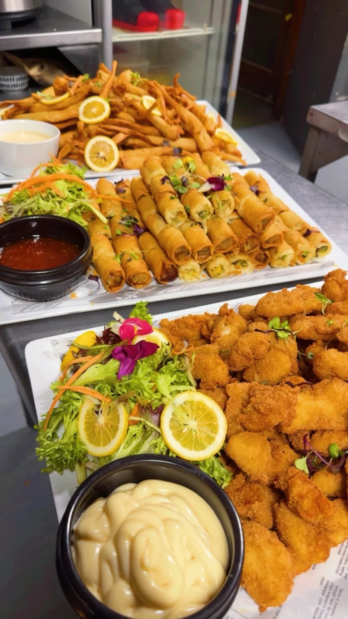 Function catering platters with spring rolls, breaded bites and dipping sauces in the kitchen