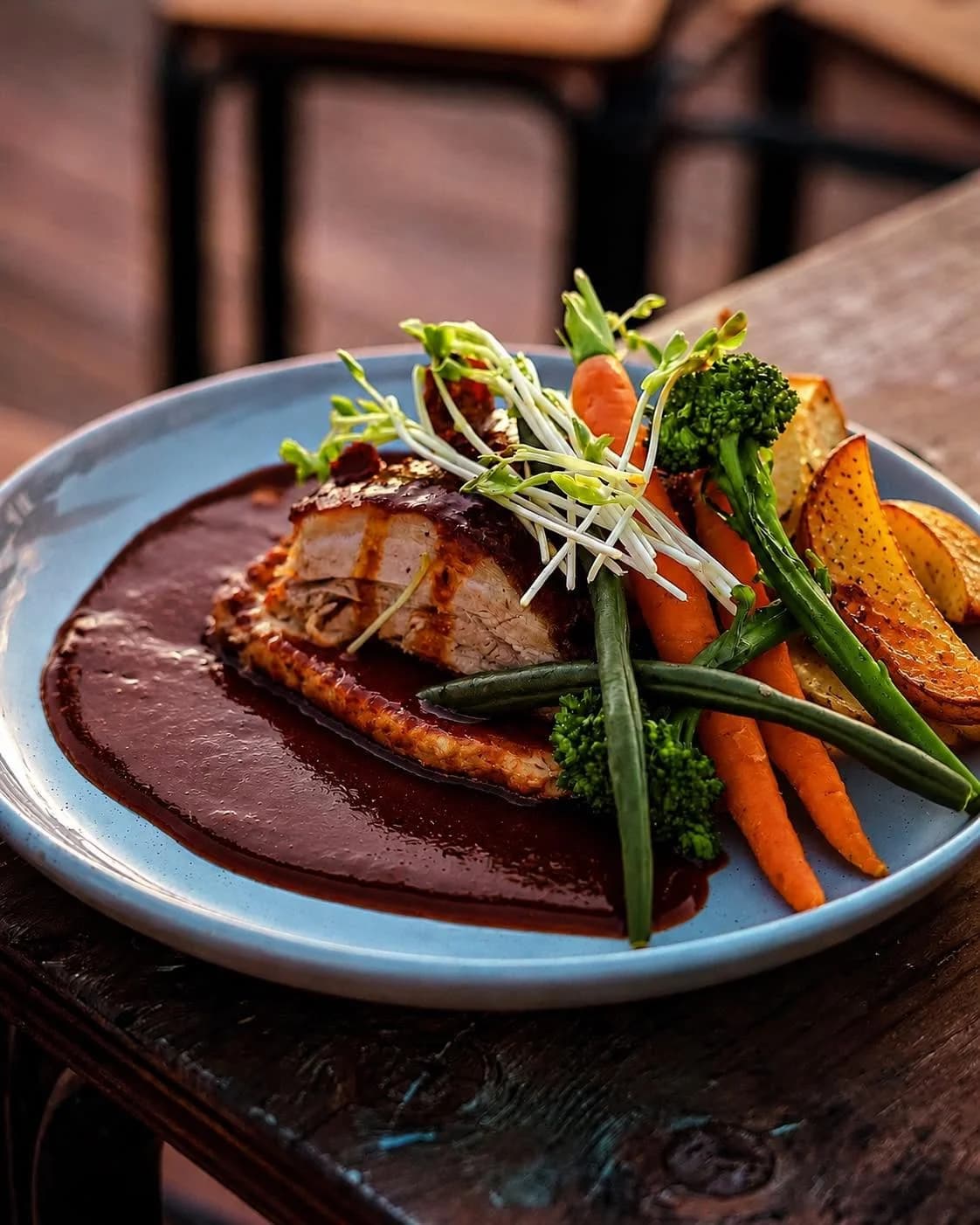 Roasted pork belly with crackling, baby carrots, broccolini and potato wedges