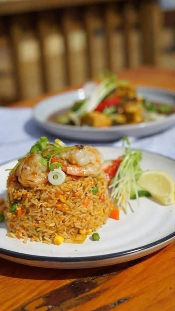 Thai fried rice topped with grilled prawns, scallions and a lemon wedge
