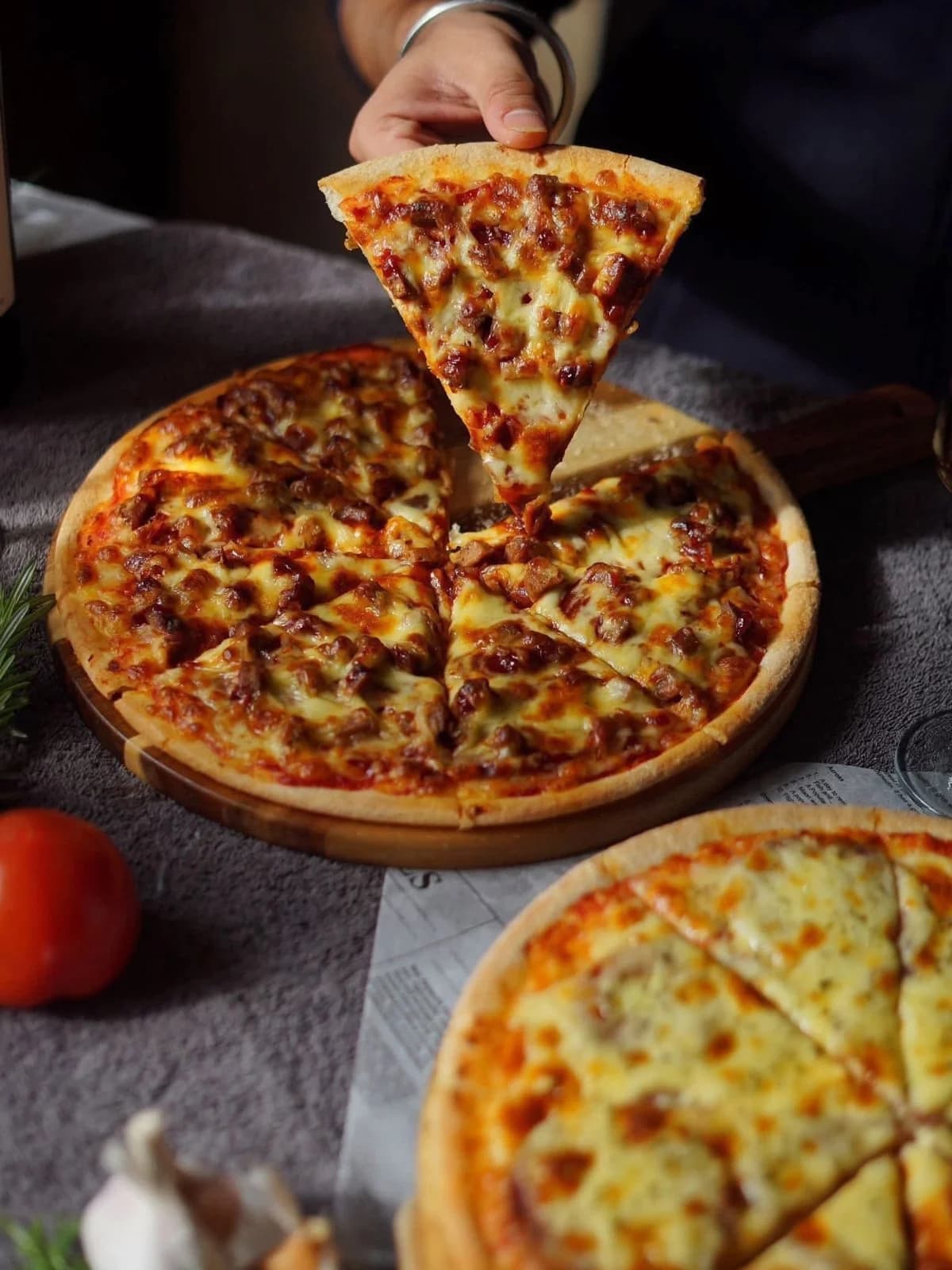 Stone-baked pizza slice being lifted from a whole pizza on a wooden board