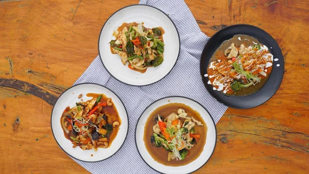 Selection of Thai stir-fry dishes and curries on a wooden table