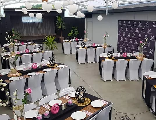 Function room with white chair covers and pink table décor