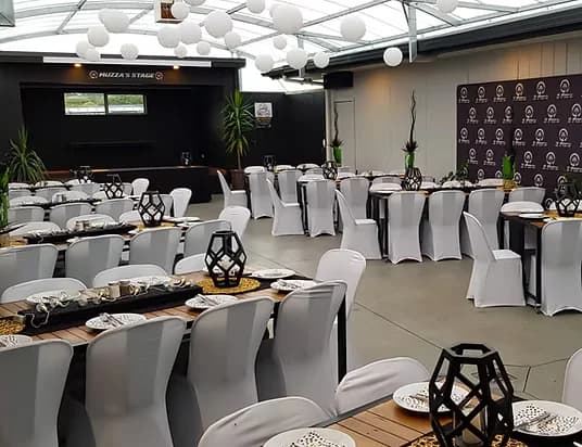 Function room with white chair covers and stage at Three Furlongs